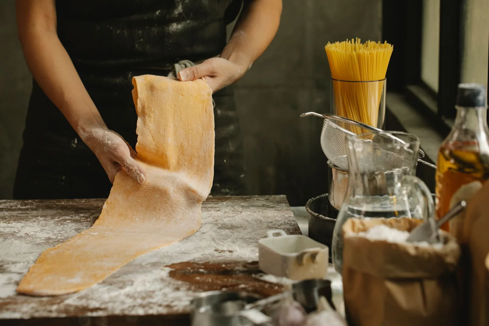 Des mains étalent une pâte sur une planche farinée.