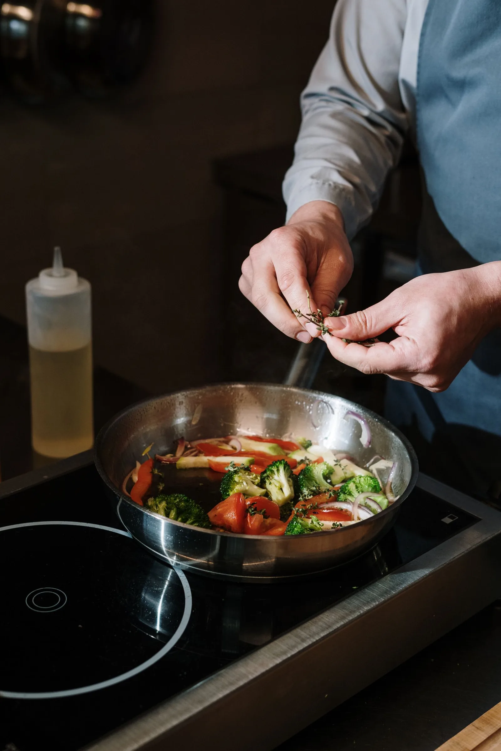 Des légumes sont assaisonnés dans une poêle.
